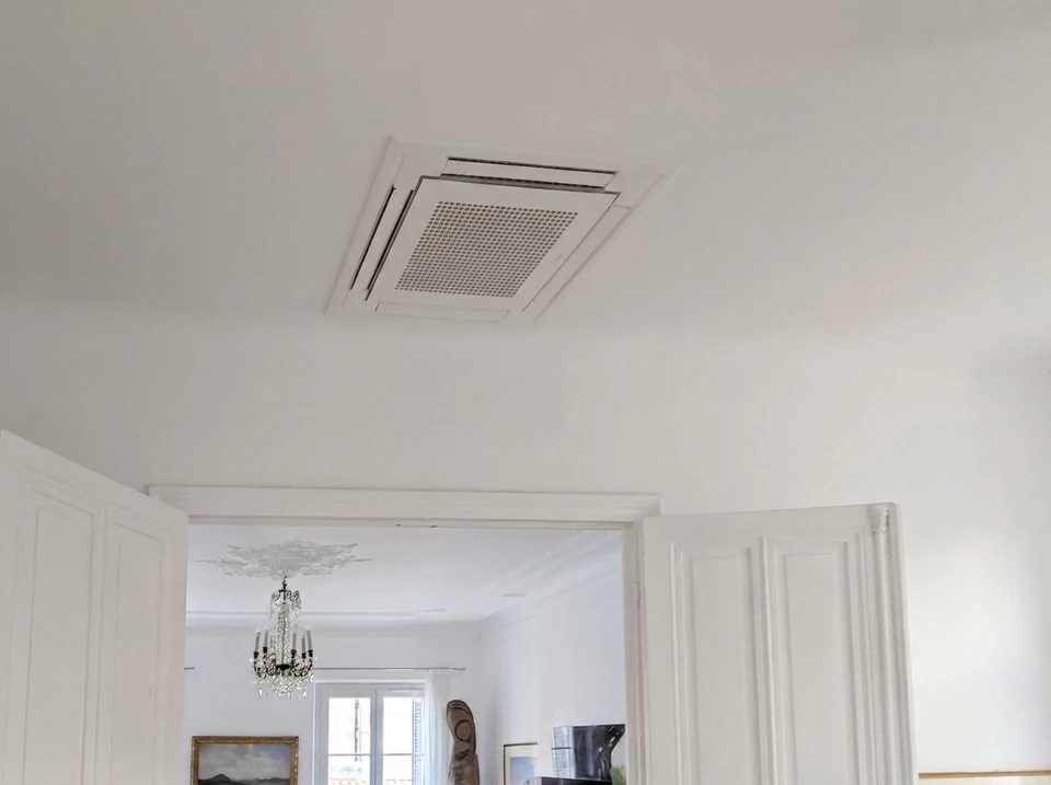 Intérieur blanc épuré avec double porte à panneaux moulurés ouverte sur une salle à manger ornée d'un lustre à bougies en cristal et médaillon de plafond